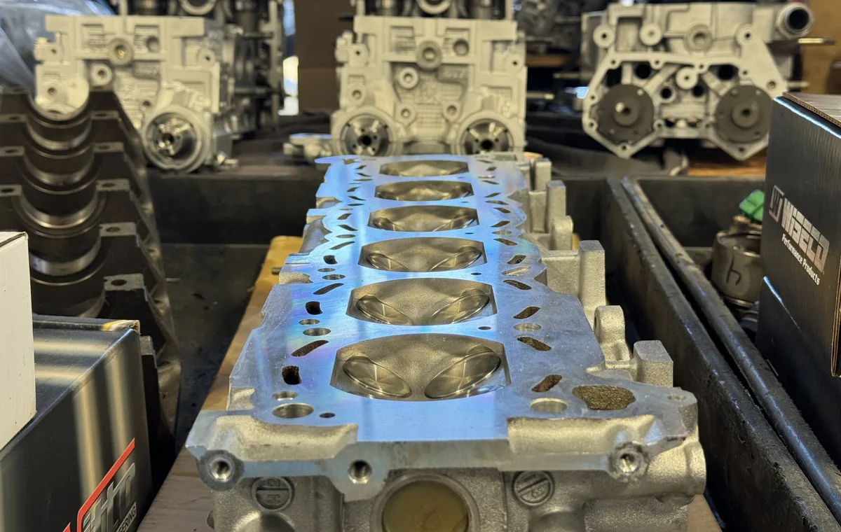 A freshly decked Subaru cylinder head with newly cut combustion chambers, racked engine blocks behind it