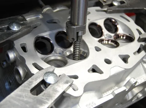 Close-up of a piloted cutter entering a valve port on a clamped cylinder head