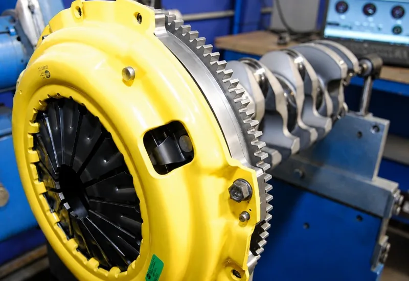 A clutch pressure plate and flywheel bolted to a crankshaft set up on a balancing machine